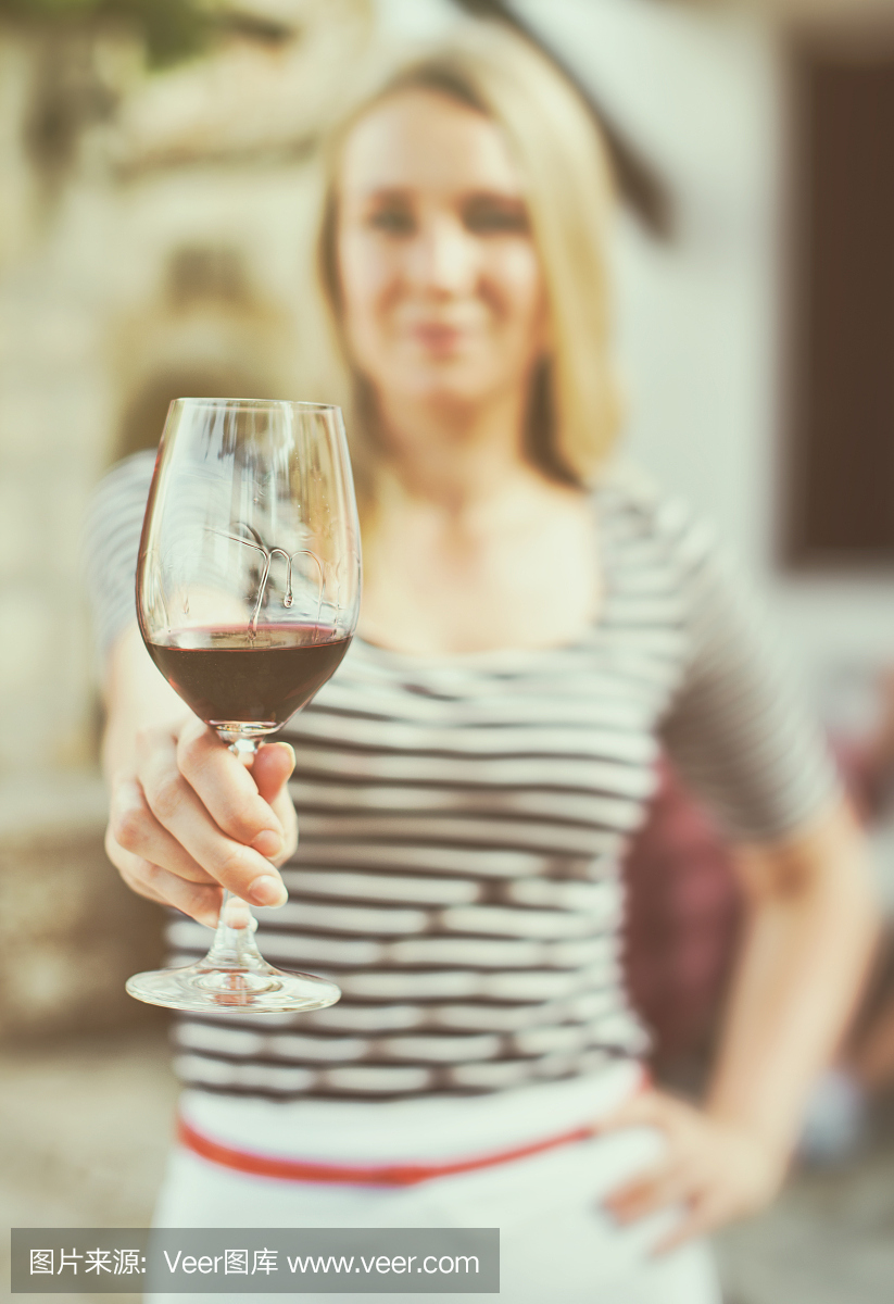 一個女人在室外遞上一杯紅酒。復古的效果。